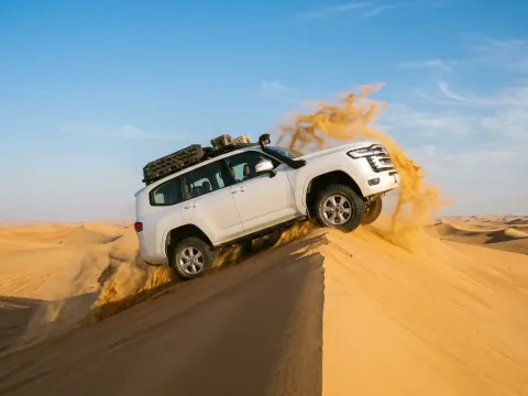 4x4 dune bashing cresting a sand dune in the morning light