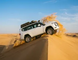 4x4 dune bashing cresting a sand dune in the morning light