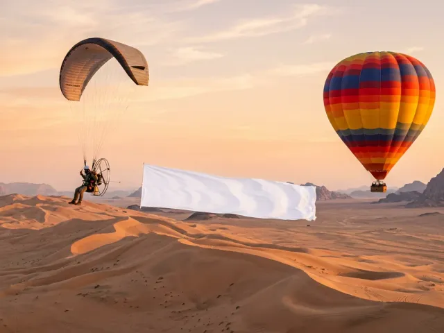 Paramotor flying a banner past a hot air balloon for a proposal